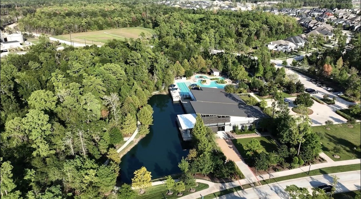 Aerial view of a wooded Spring, Texas neighborhood amenity lake and pool
